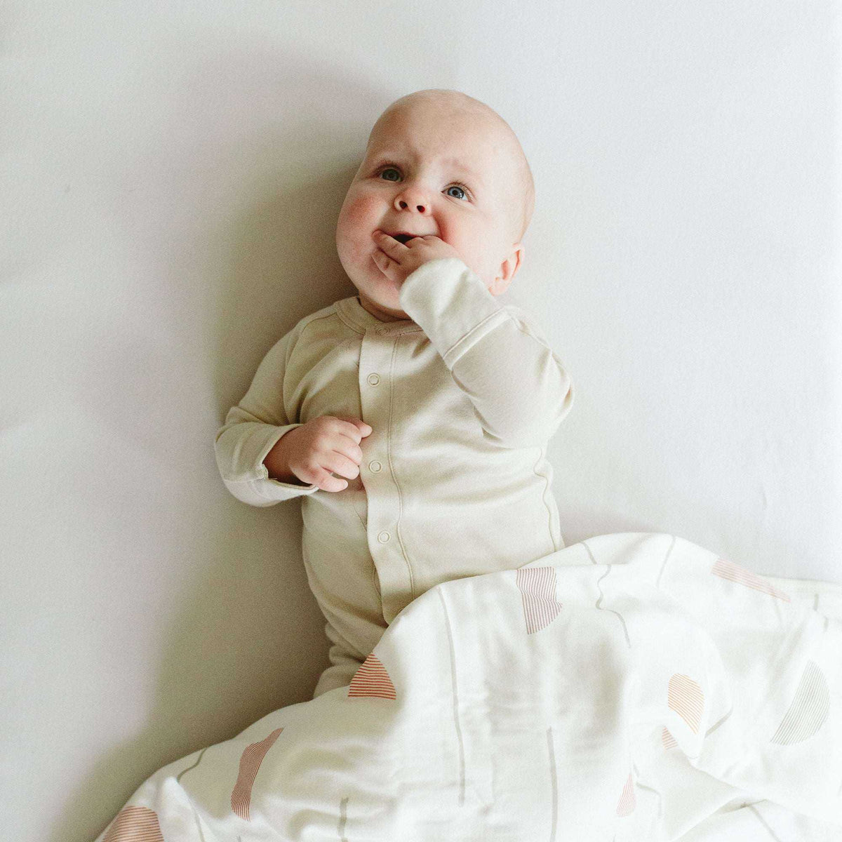 24 HOUR CONVERTIBLE GOWN in soft birch cream fabric, worn by a baby, with covered hands and snap front