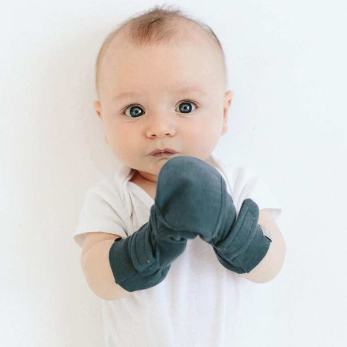 BABY MITTENS in deep midnight blue, soft fabric with adjustable wraparound closures covering a baby's hands