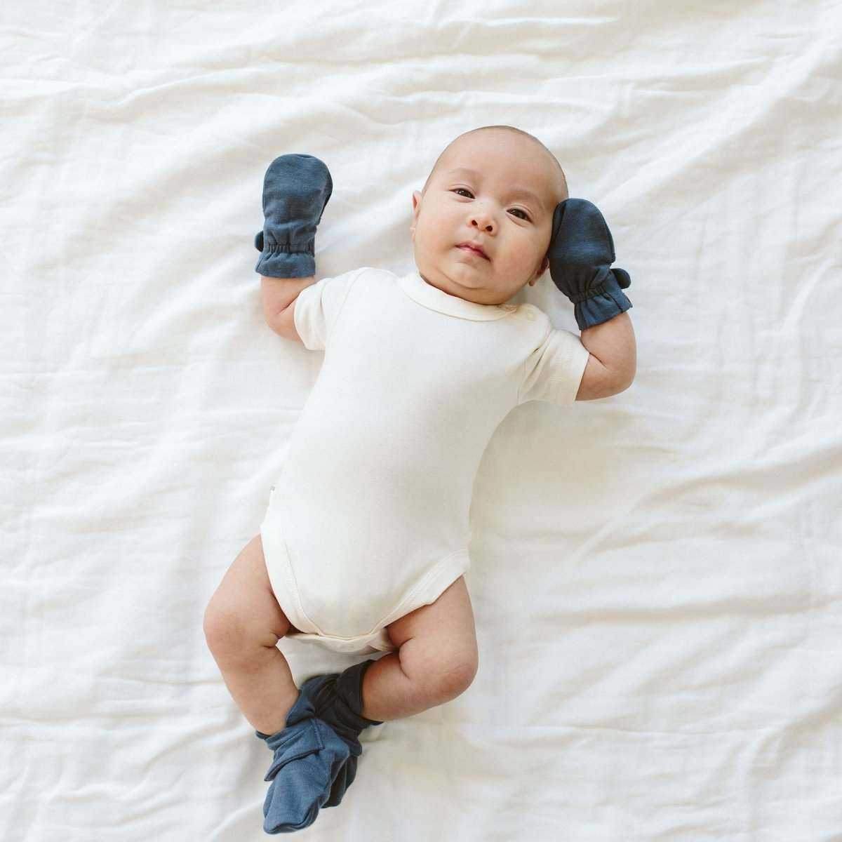 BABY MITTENS in deep midnight blue, soft fabric with gathered adjustable cuffs, worn by an infant