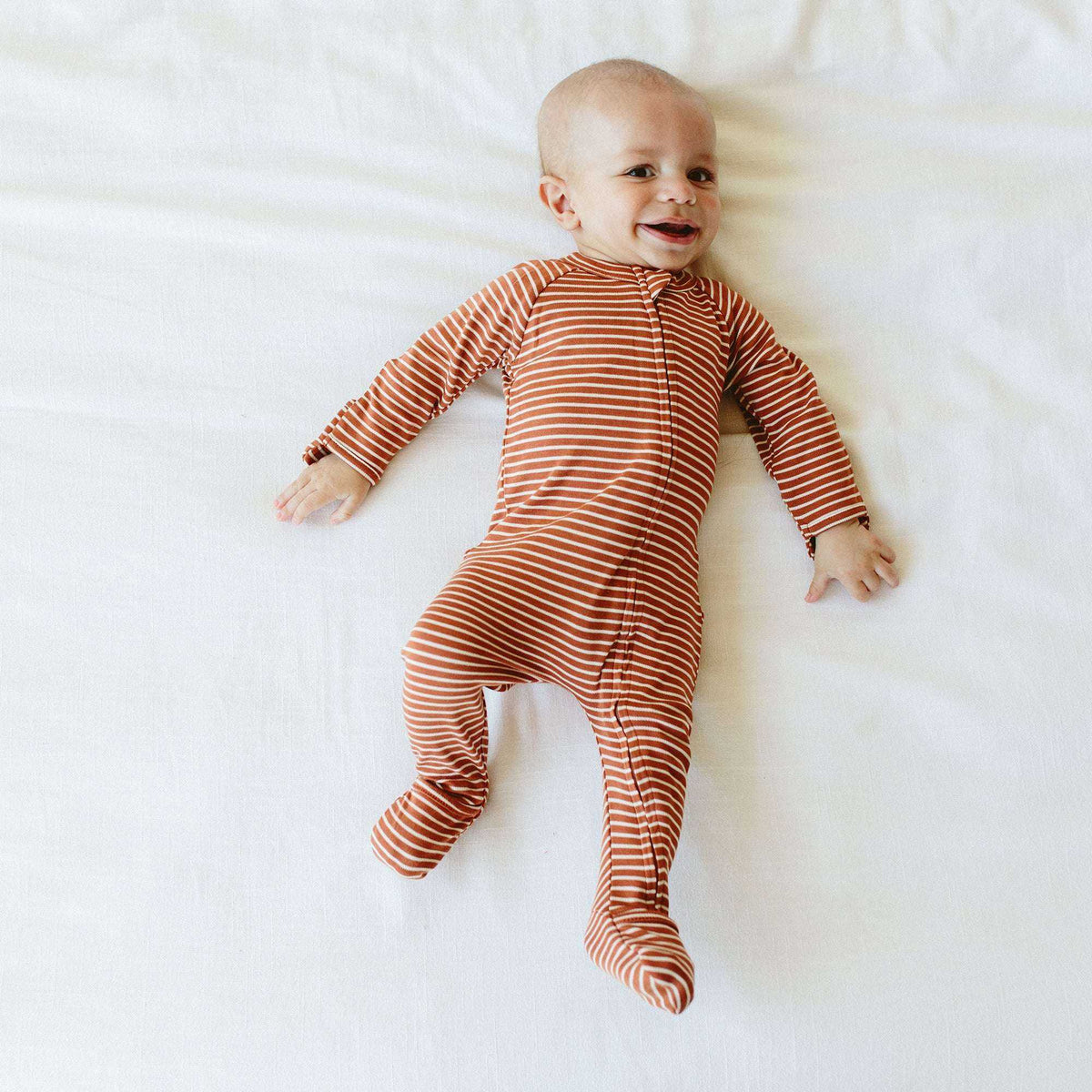 GROW WITH YOU FOOTIE in soft clay-orange and cream striped fabric, featuring a long-sleeve zip-up design with enclosed feet