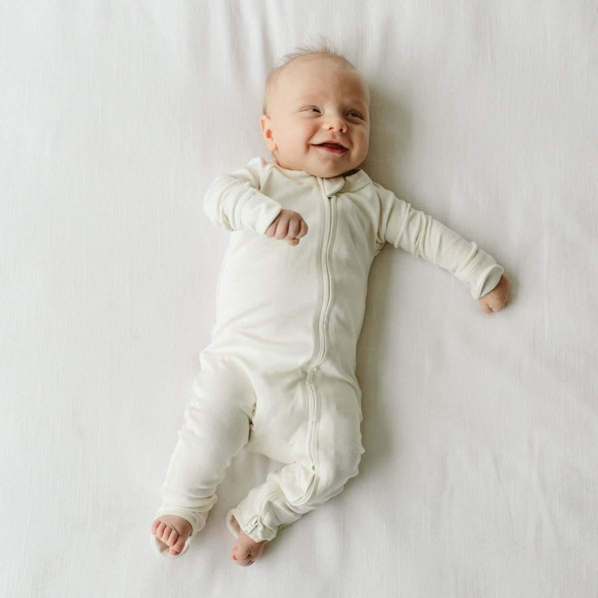 GROW WITH YOU FOOTIE in soft cloud ivory fabric, featuring long sleeves, a two-way front zipper and convertible feet