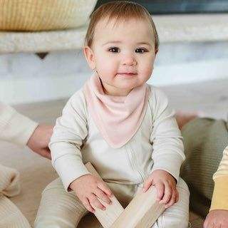 GROW WITH YOU FOOTIE baby romper in cream with ribbed fabric, worn with a soft blush-pink bandana bib