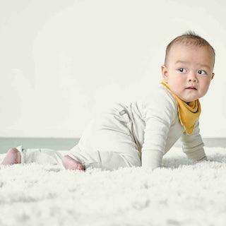 GROW WITH YOU FOOTIE in ivory, a soft long-sleeve baby footie with a front zipper and mustard yellow bib neckline