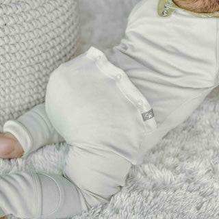 GROW WITH YOU FOOTIE in soft white fabric, featuring a two-way zipper and fold-over cuffs on the sleeves and feet