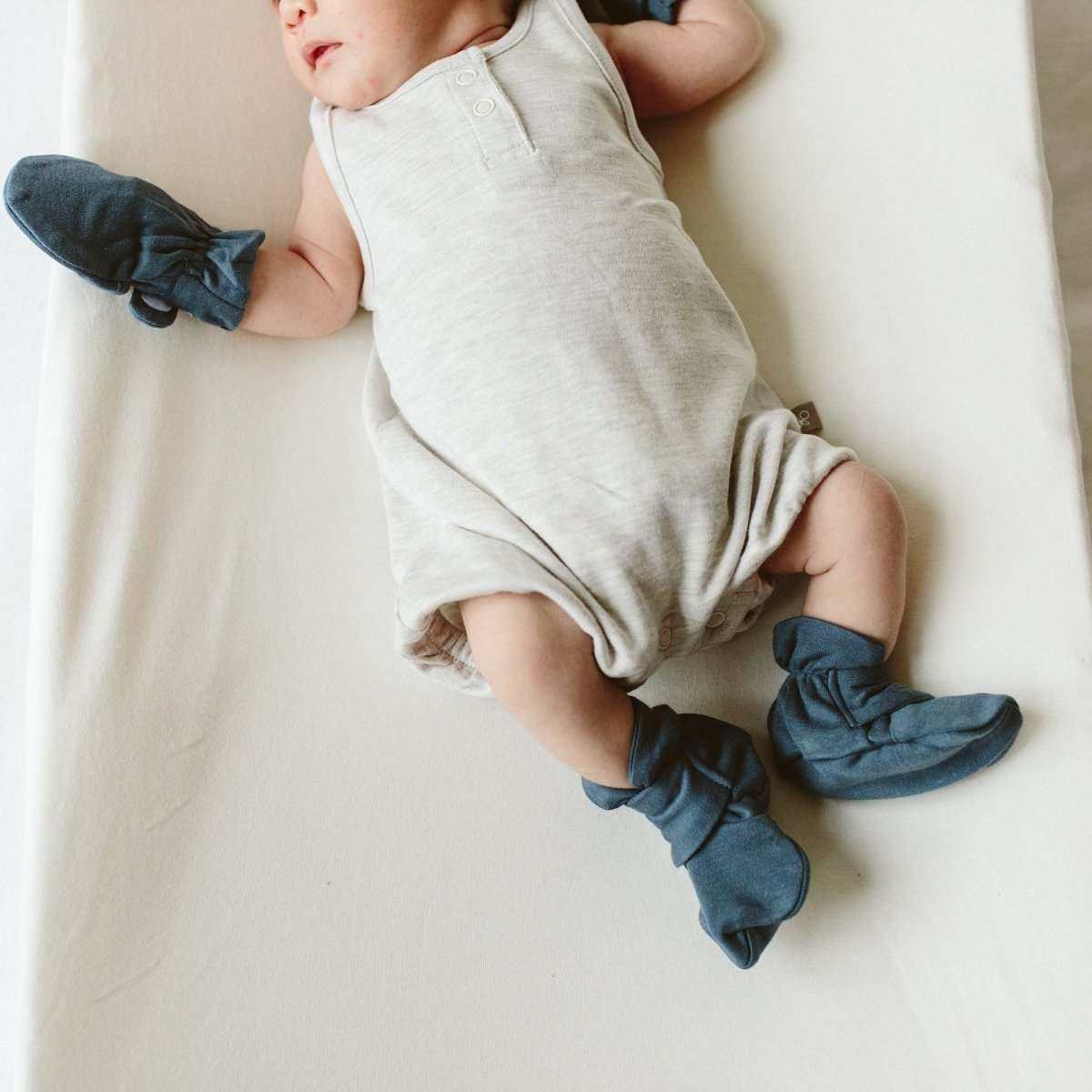 PREEMIE STAY ON BOOTS in midnight blue soft fabric, with gathered cuffs and adjustable closures on a baby’s feet