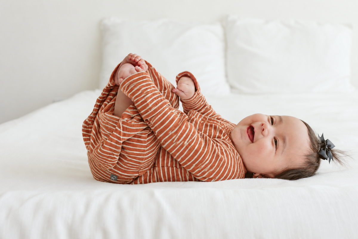 Quiet Night Starter Set baby gown in rust clay with cream stripes, featuring a soft long-sleeve convertible design