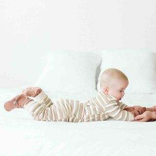 STAY ON 2-PACK BOOTS in soft cream fabric with thin brown stripes, shown on a baby with adjustable wraparound closures