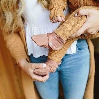 STAY ON 2-PACK BOOTS in soft dusty pink fabric, shown on a baby with an adjustable wraparound closure