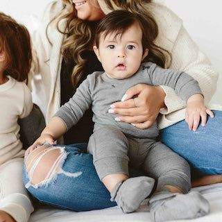 STAY ON 2-PACK MITTS shown on a baby wearing a gray outfit, with soft gray mitts covering both hands