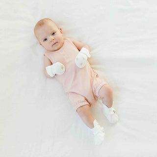 STAY ON 2-PACK MITTS in white, soft fabric with adjustable cuffs, worn by a baby with a pale pink outfit