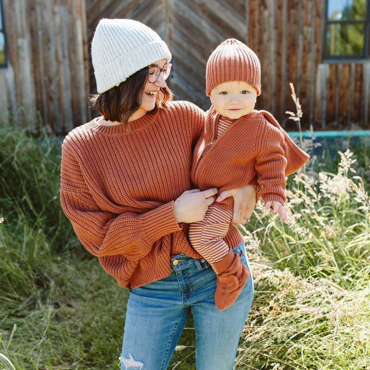 Stay on Knit Boots in rust-colored ribbed knit with a soft cuff and adjustable wrap closure, worn by a baby