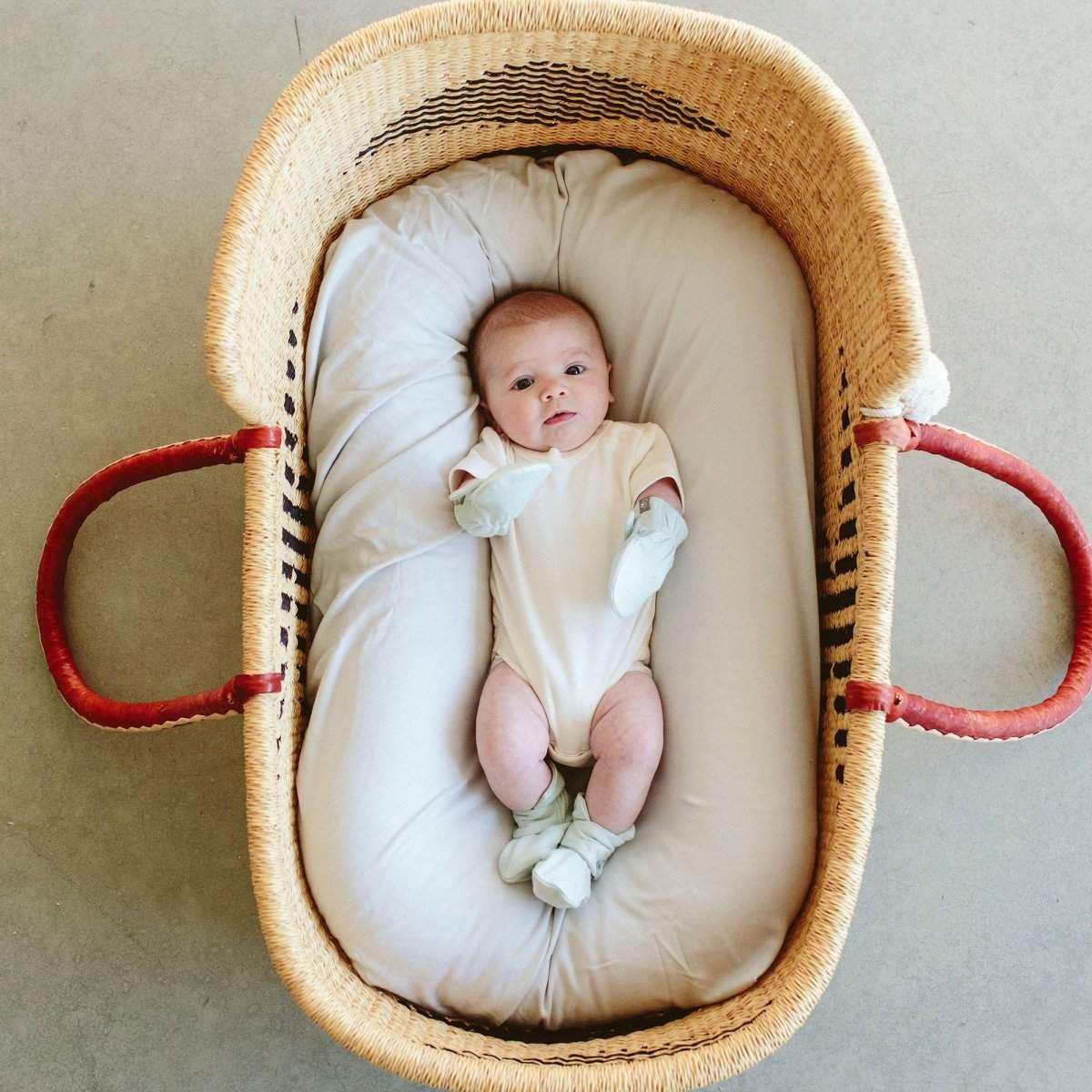 STAY ON MITTS shown as soft pale green baby mitts worn by an infant in a cream outfit