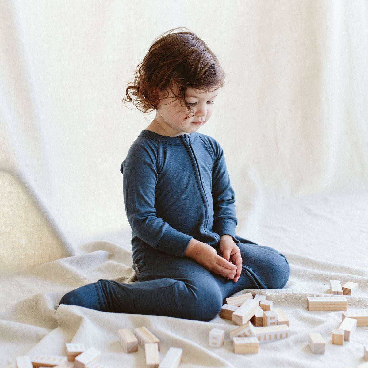 Welcome Home Set features a child wearing a solid midnight blue zip-up footie with long sleeves and covered feet