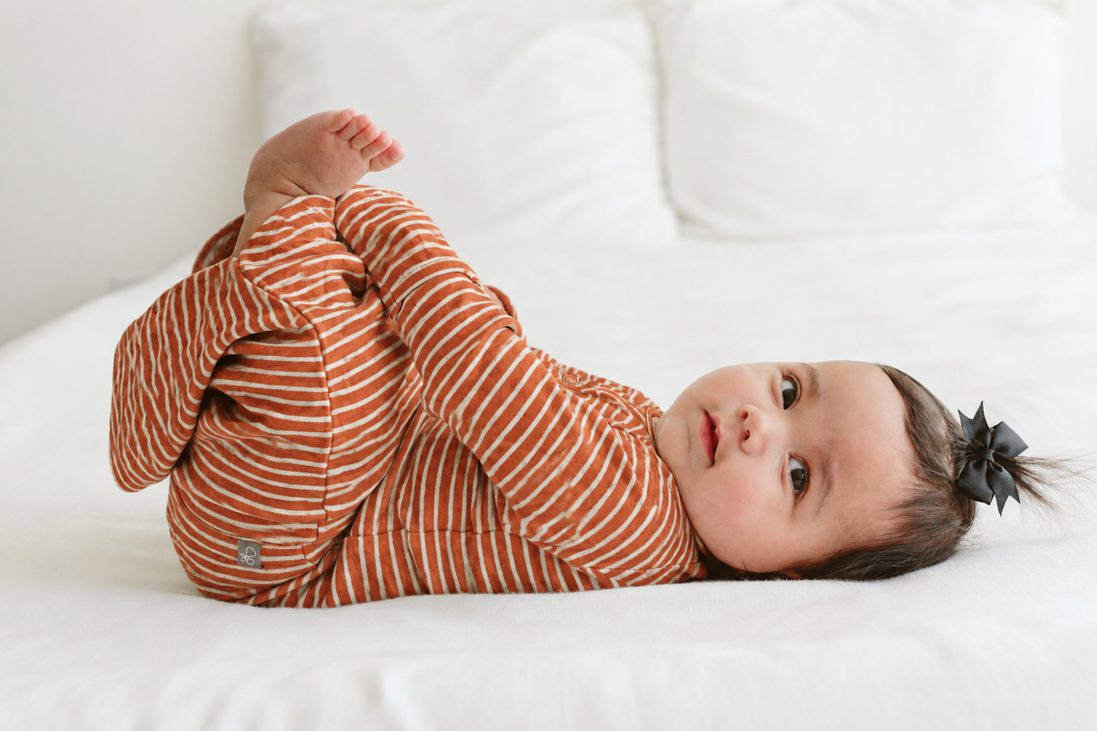 Welcome Home Set featuring a baby wearing a rust and cream striped convertible gown with a dark bow headband