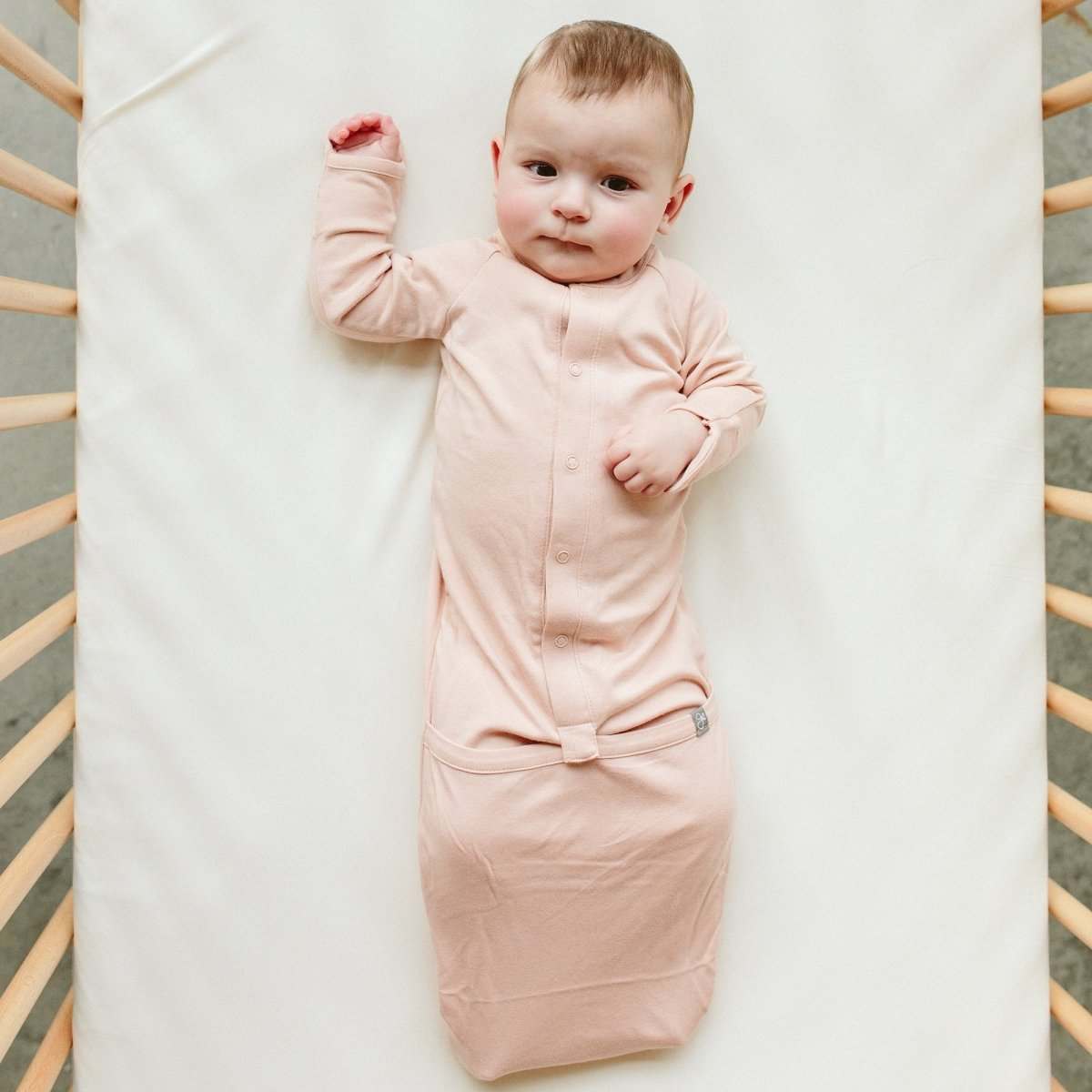 24 HOUR CONVERTIBLE GOWN in blush pink bamboo cotton, worn by a baby with snap front and convertible hem