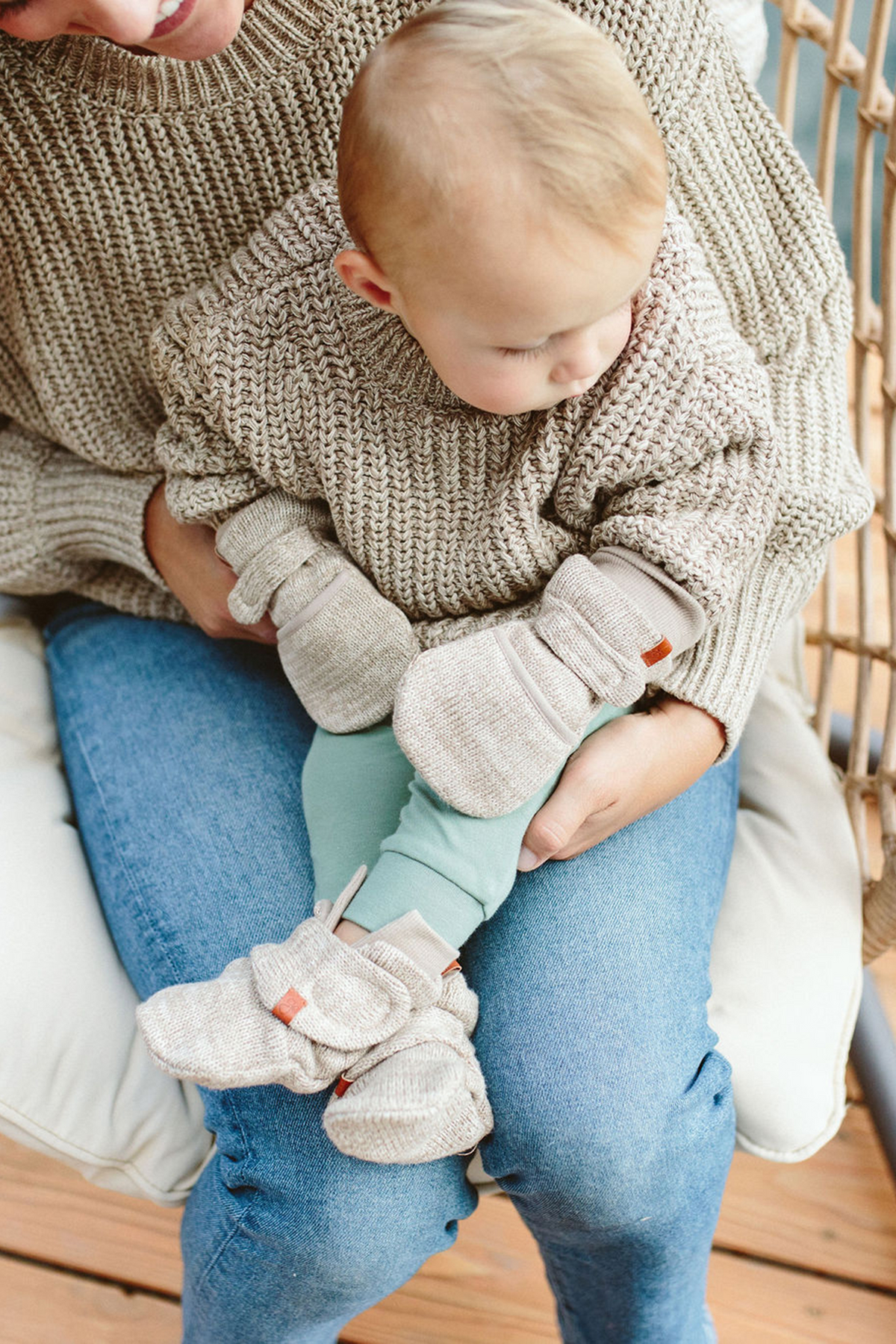 KNIT MITTS in soft oatmeal knit cotton with chunky ribbed cuffs and small leather labels, worn by a baby