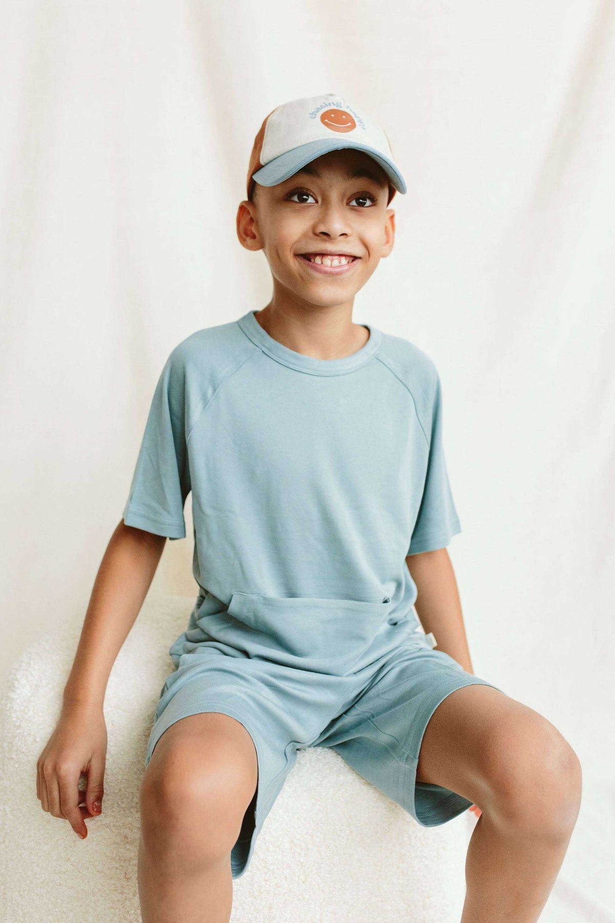 BALL CAP in white with pale blue brim and orange circular emblem, featuring a curved visor and adjustable back