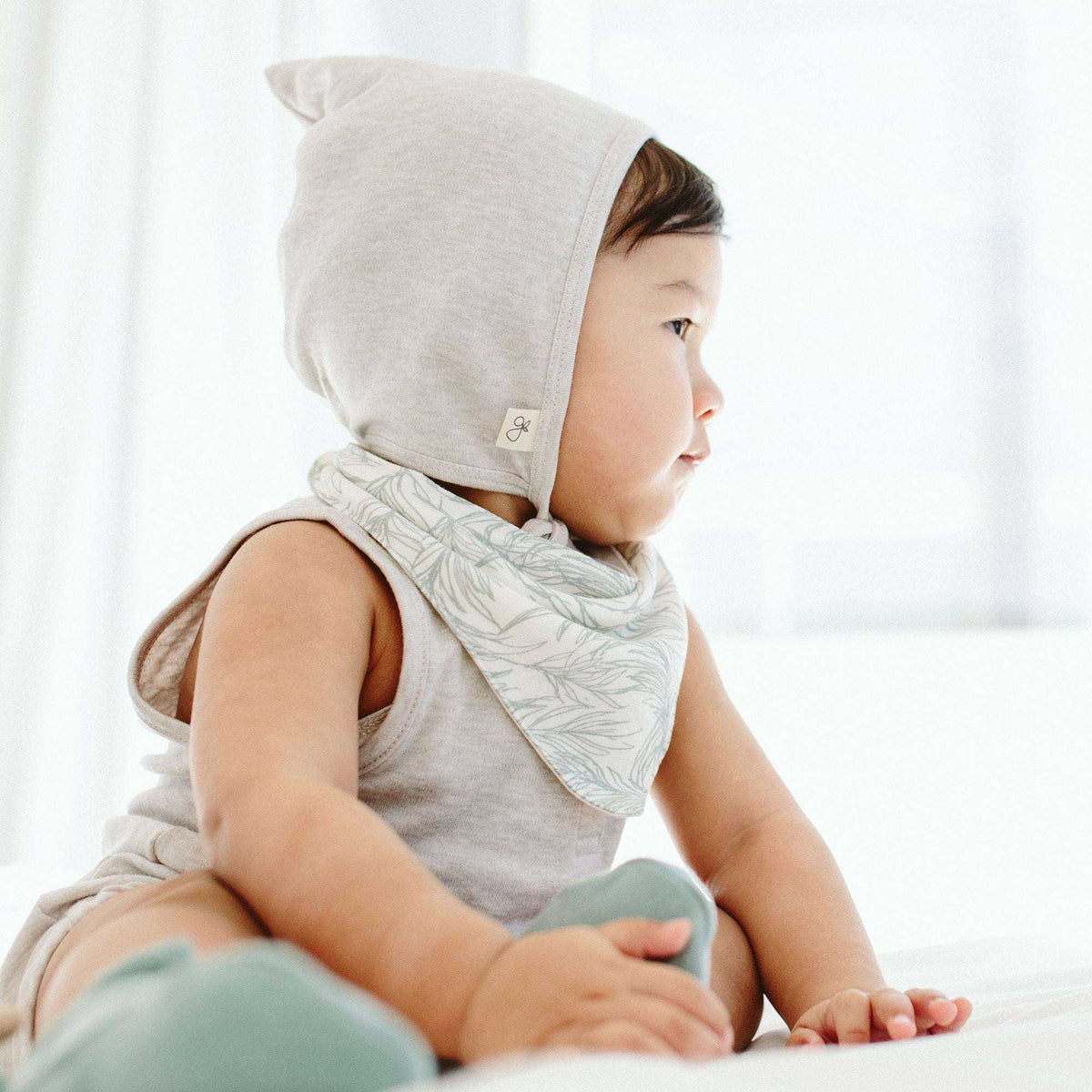 BANDIT BONNET in soft storm gray cotton blend, with a fitted pixie shape and small side label on a baby