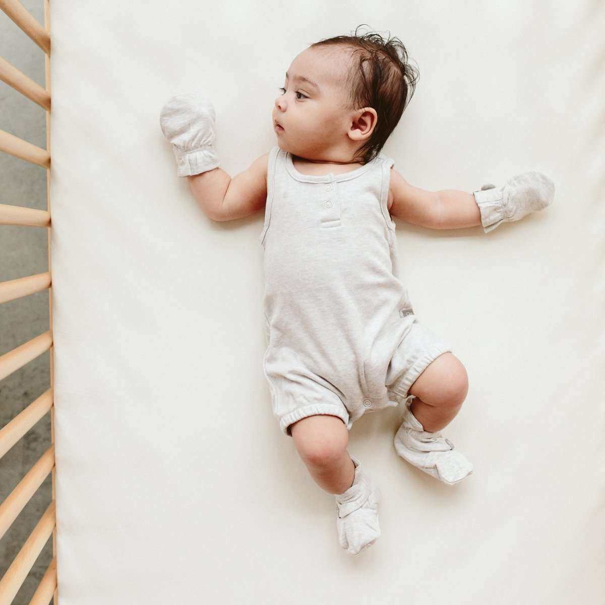 PREEMIE STAY ON MITTS in light gray soft fabric with subtle patterned cuffs, worn by a baby
