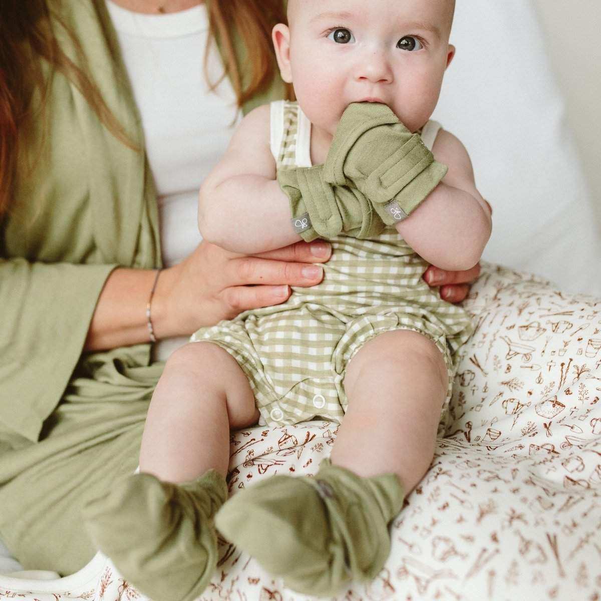STAY ON BOOTS in sage green soft fabric with adjustable wrap closures, worn by a baby with a gingham romper