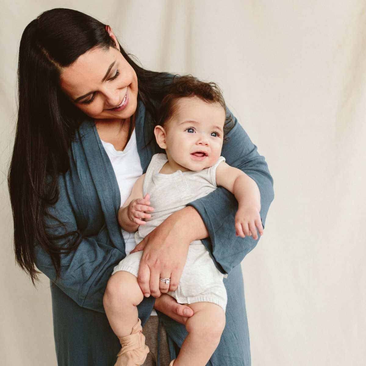 WOMENS ROBE in a muted blue-gray fabric, worn with a wrap belt and three-quarter sleeves while holding a baby